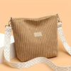 Sac à épaule et bandoulière en velours côtelé beige avec une sangle à motif blanc, présenté sur fond clair.