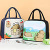 A cartoon capybara insulated lunch bag with a light background and green accents, shown next to silverware.