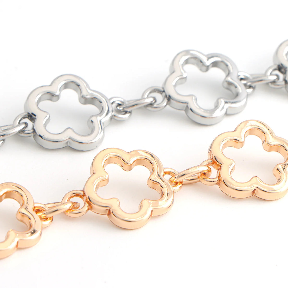 A pair of flower-shaped extender chains, one silver and one gold, displayed against a white background.