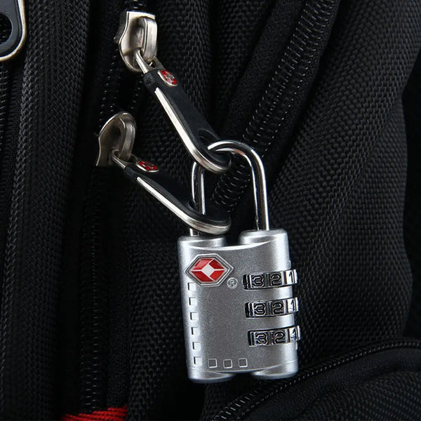 A silver TSA security combination lock attached to a black zipper pull on a jacket.