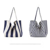 A striped canvas tote bag featuring vertical navy and white stripes with a gathered top design.