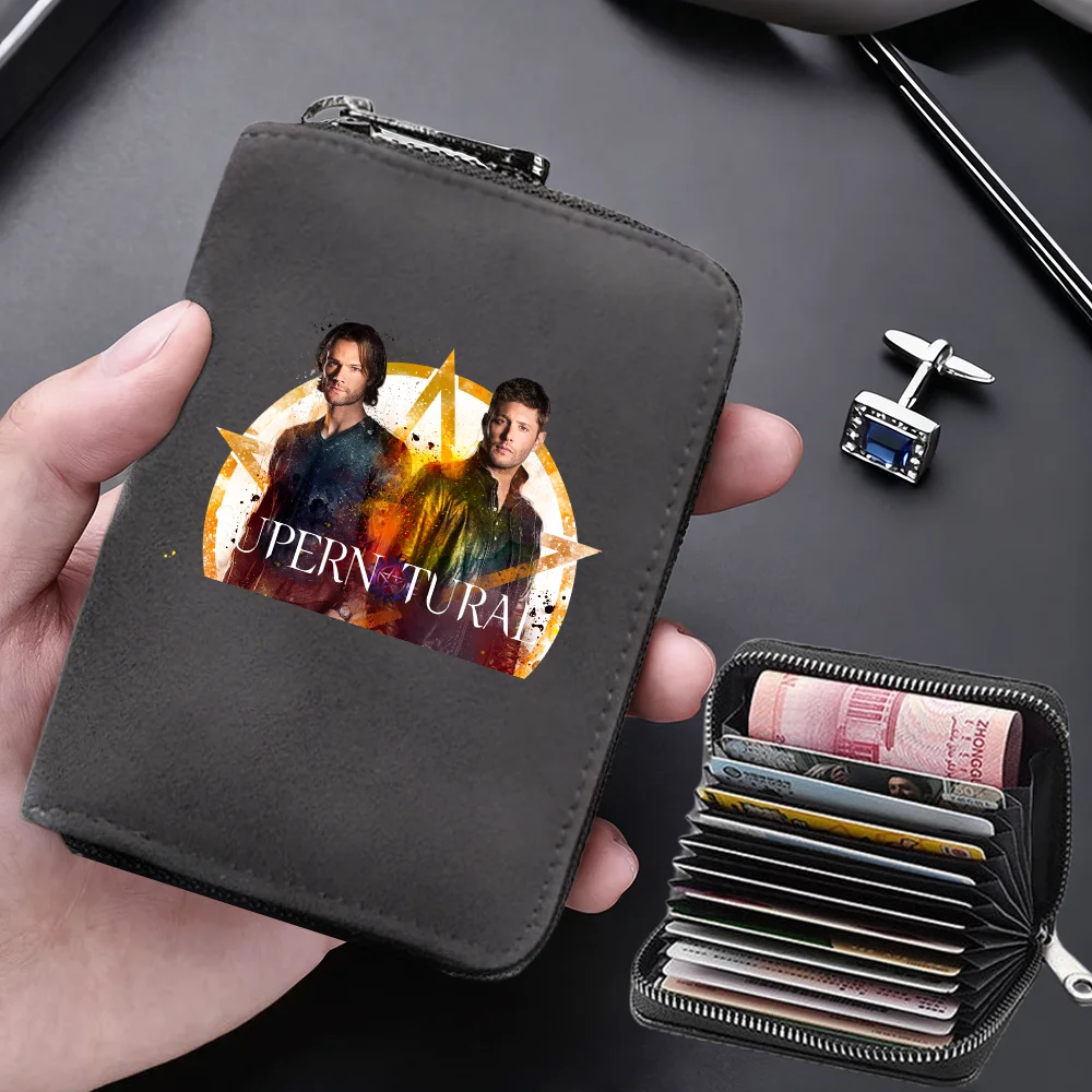 A dark gray compact RFID-blocking card wallet is held in a hand, featuring a graphic design of two men and text on the cover.