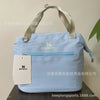 Light blue Stanley insulated cooler lunch bag with a gray strap displayed on a dark surface.