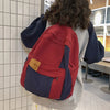 A person is wearing a red and navy canvas fashion backpack for students and travel.