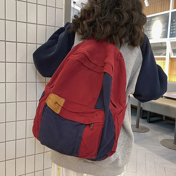 A person is wearing a red and navy canvas fashion backpack for students and travel.