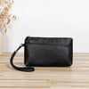 Black retro PU leather zipper wrist bag resting on a light wooden surface.