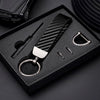 A black box holds a carbon fiber leather keychain with a silver clasp and a small tool.
