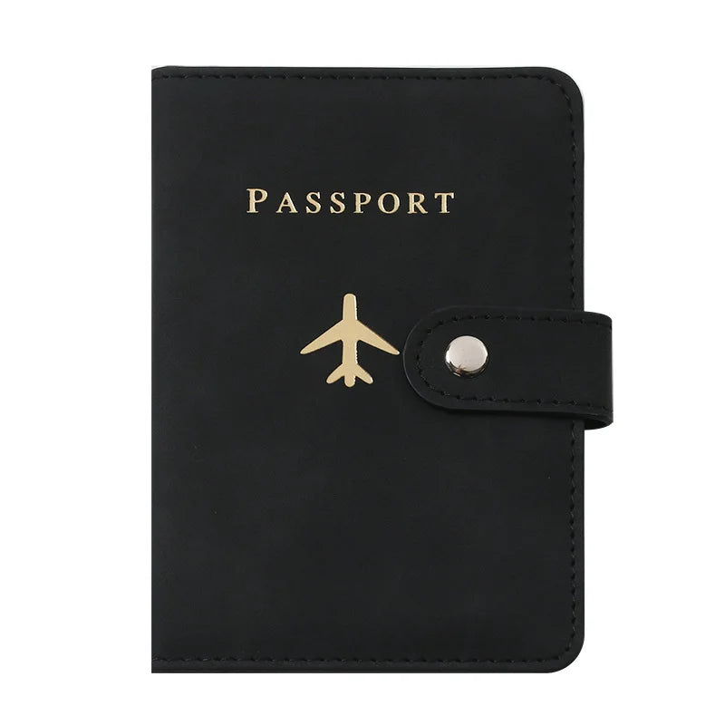 Porte-passeport en cuir noir avec lettres dorées et fermeture à pression argentée.