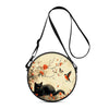 A round black and orange cartoon cat crossbody bag with a leather strap.