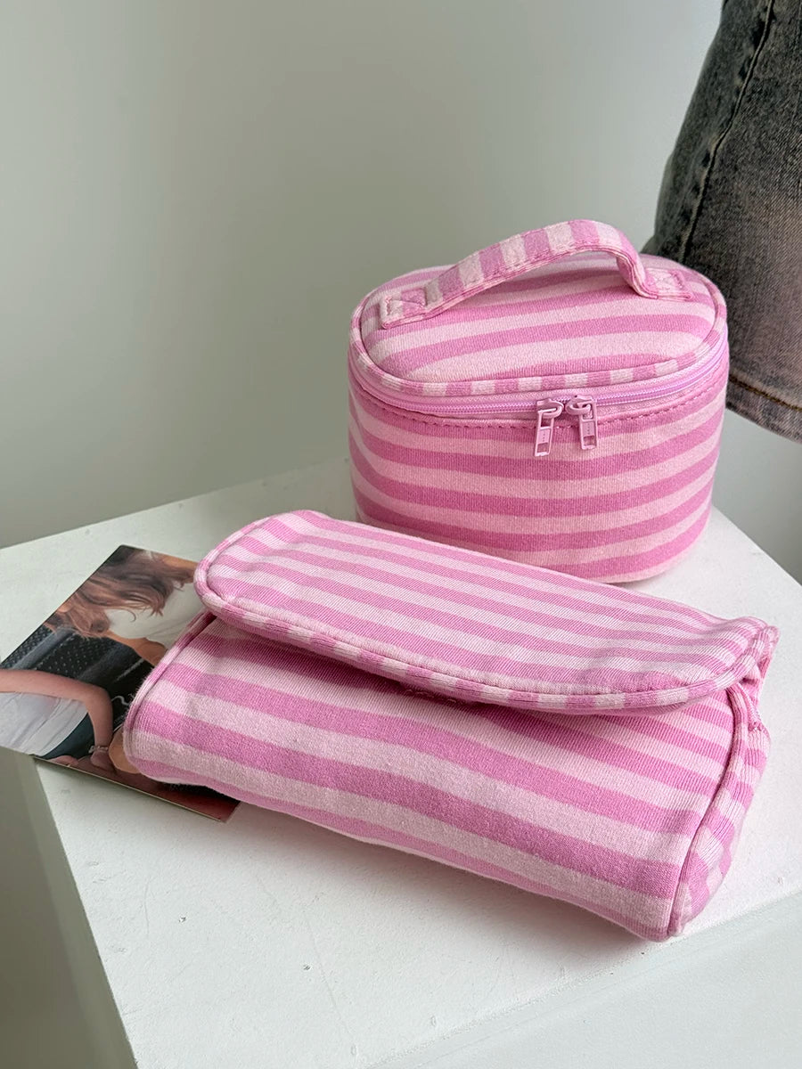 A pink striped Y2K makeup bag with a zipper and a fitted pouch is displayed on a white surface.