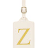 Étiquette de bagage beige en cuir rectangulaire avec un Z brodé en or et une pince métallique argentée.