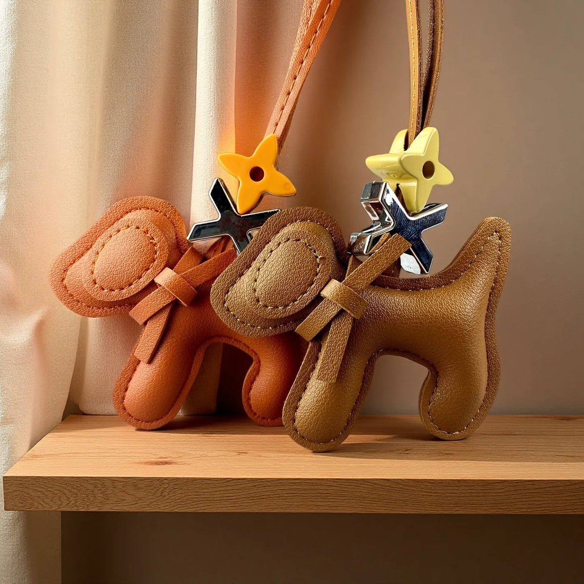 A tan PU leather puppy charm with a bow tie and yellow flower accents hanging from a brown leather strap.