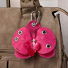 A pink orchid flower keychain is attached to a tan leather handbag.
