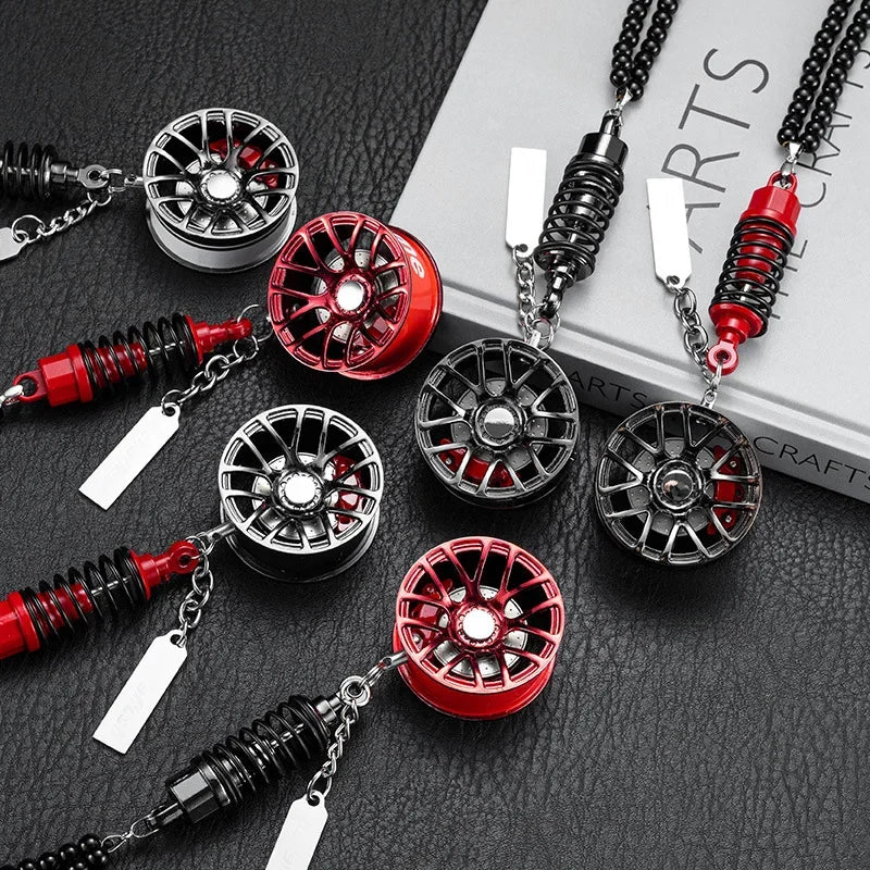 A collection of black and red alloy wheel hub brake disc rearview mirror pendants displayed on a dark surface.