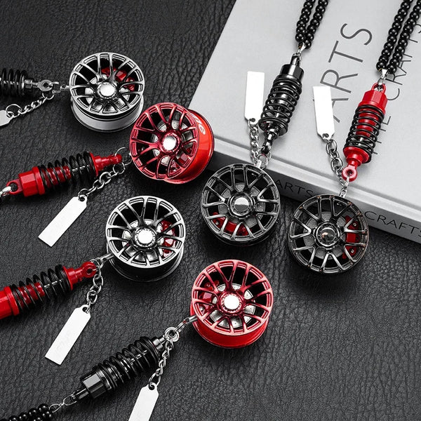 A collection of black and red alloy wheel hub brake disc rearview mirror pendants displayed on a dark surface.