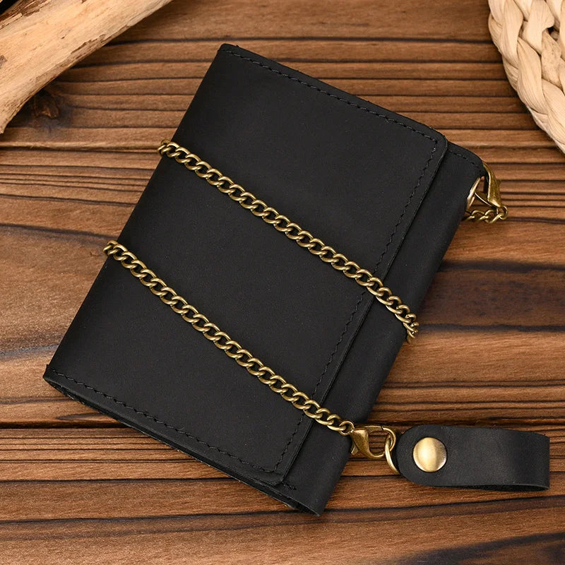 Black men's genuine leather trifold wallet with a gold chain resting on a wooden surface.