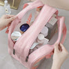 A pink double-layer clear and dry wash bag for travel is shown being held by a hand.