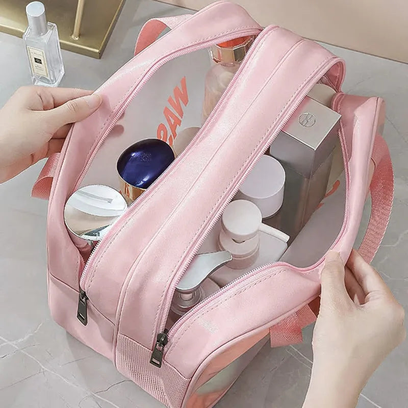A pink double-layer clear and dry wash bag for travel is shown being held by a hand.