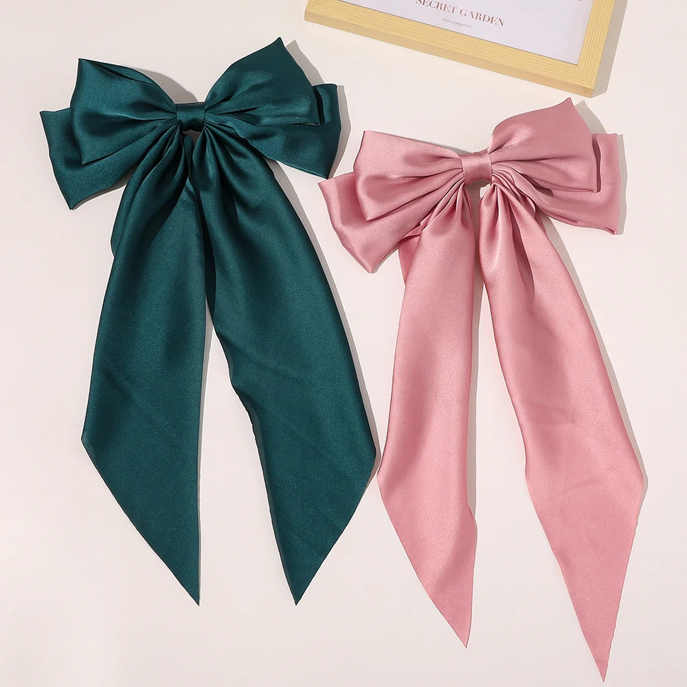 A pair of elegant silk bows in deep emerald green and soft pink, displayed next to a framed card.