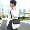 A young man wearing a white jacket and dark pants holds a black PU leather shoulder clutch bag.