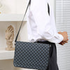 A person wearing a white shirt carries a gray patterned flap crossbody bag with a black strap.