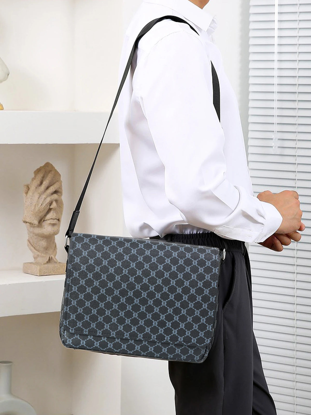 A person wearing a white shirt carries a gray patterned flap crossbody bag with a black strap.