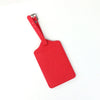 A bright red PU leather luggage tag with a silver clip attached to a strap.
