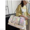 A woman holds a pink iridescent nylon travel bag with gray straps in front of a white cabinet.