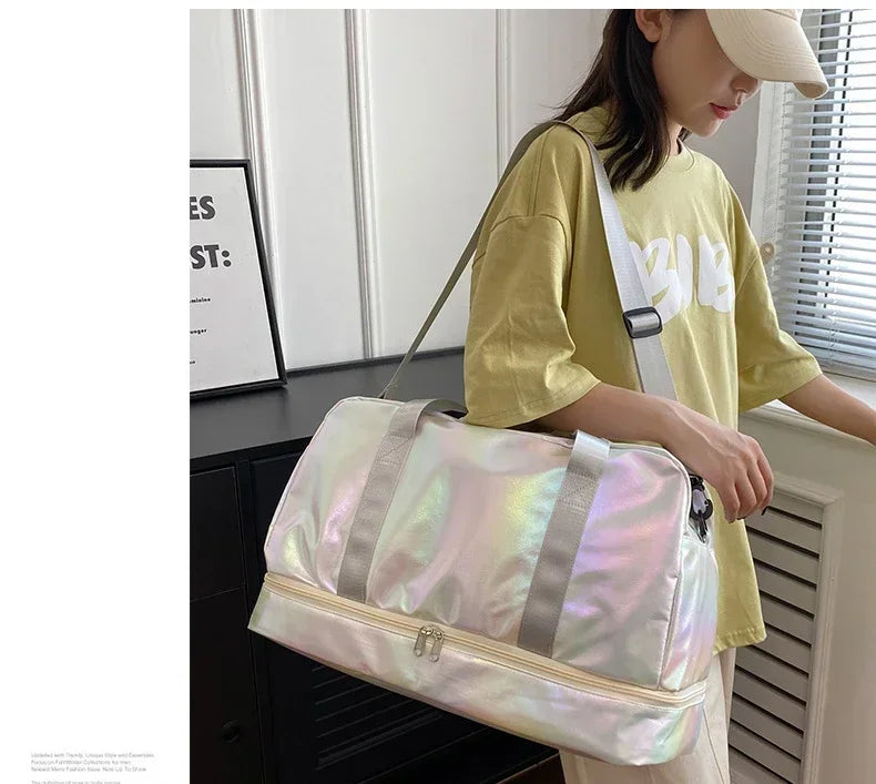 A woman holds a pink iridescent nylon travel bag with gray straps in front of a white cabinet.