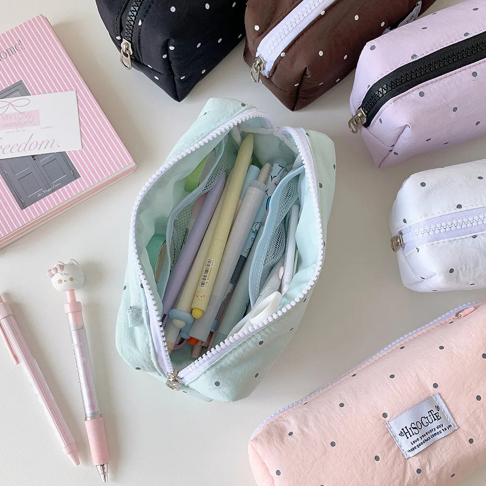Eine Sammlung von rosa, lila und beigeen Faltmappen und Schreibwaren auf einer weißen Oberfläche.