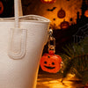 A white PU leather milk can shaped bag with a pumpkin keychain accessory in a Halloween-themed setting.
