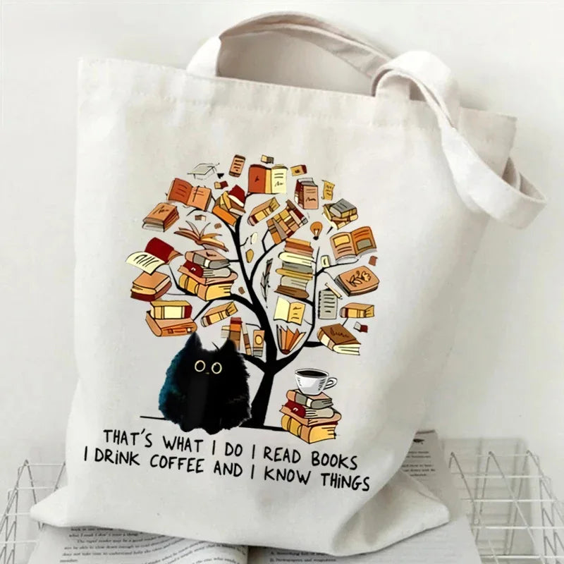 A white canvas tote bag featuring a black cat and butterfly illustration on the front.