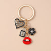 Gold-toned enamel keychain featuring a heart, a number 5, and a red lip design.