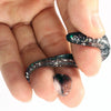 A hand holds a black adjustable soft lure fishing tackle with iridescent glitter accents.