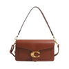 A brown leather shoulder bag with a gold initial detail and thin strap.