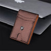 A brown leather wallet with a money clip and a silver emblem is placed on a silver laptop.