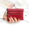 A red PU leather clutch wallet with a silver chain is shown next to a cup and some papers.