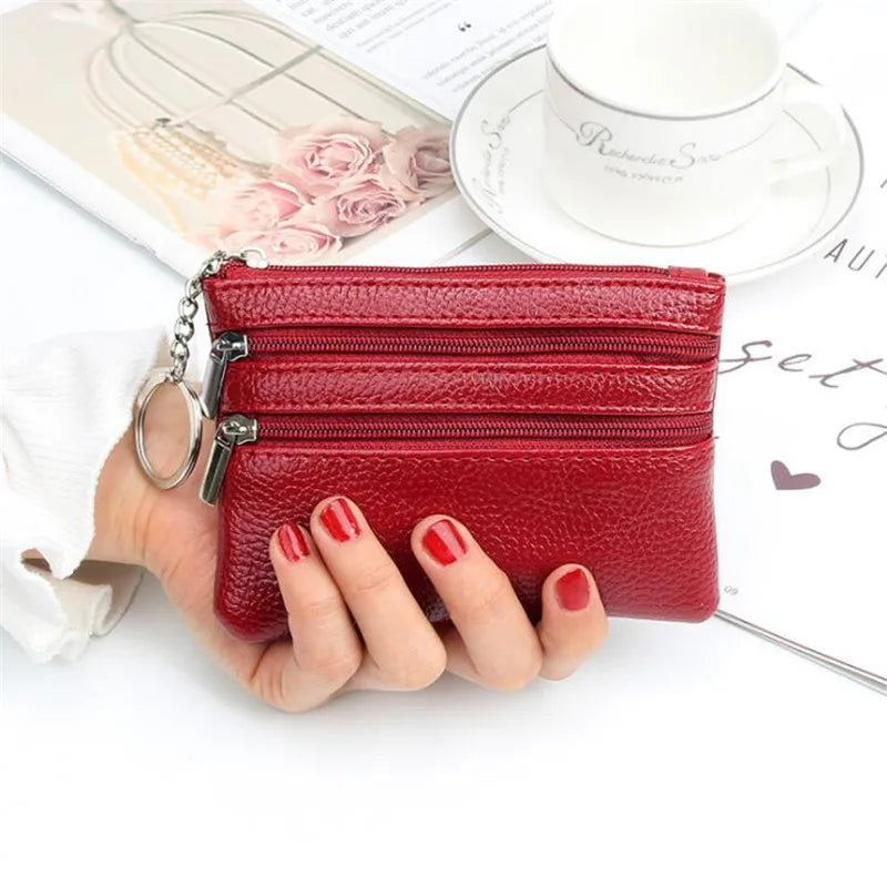 A red PU leather clutch wallet with a silver chain is shown next to a cup and some papers.
