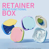 A set of pink, yellow, and blue retainer boxes for denture storage featuring a mirror and drainage.