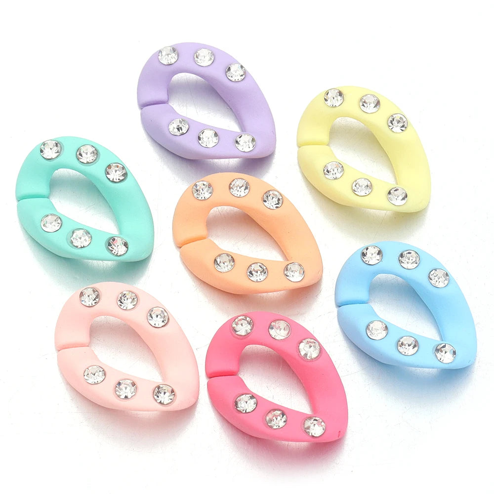 A collection of colorful acrylic link chains in lavender, yellow, mint green, peach, and blue, each adorned with small clear 