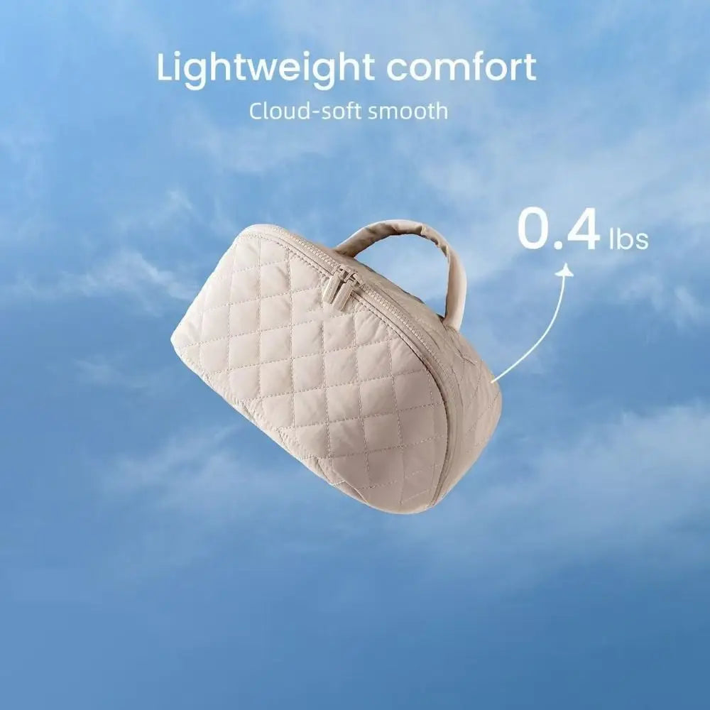 A light beige, quilted makeup organizer bag is shown against a blue sky background.