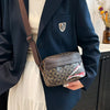 A dark blue blazer sleeve shows a brown leather crossbody coin purse with a patterned flap and a small shield emblem.