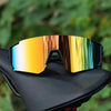 A pair of orange-tinted sunglasses with a black frame resting on a dark surface.