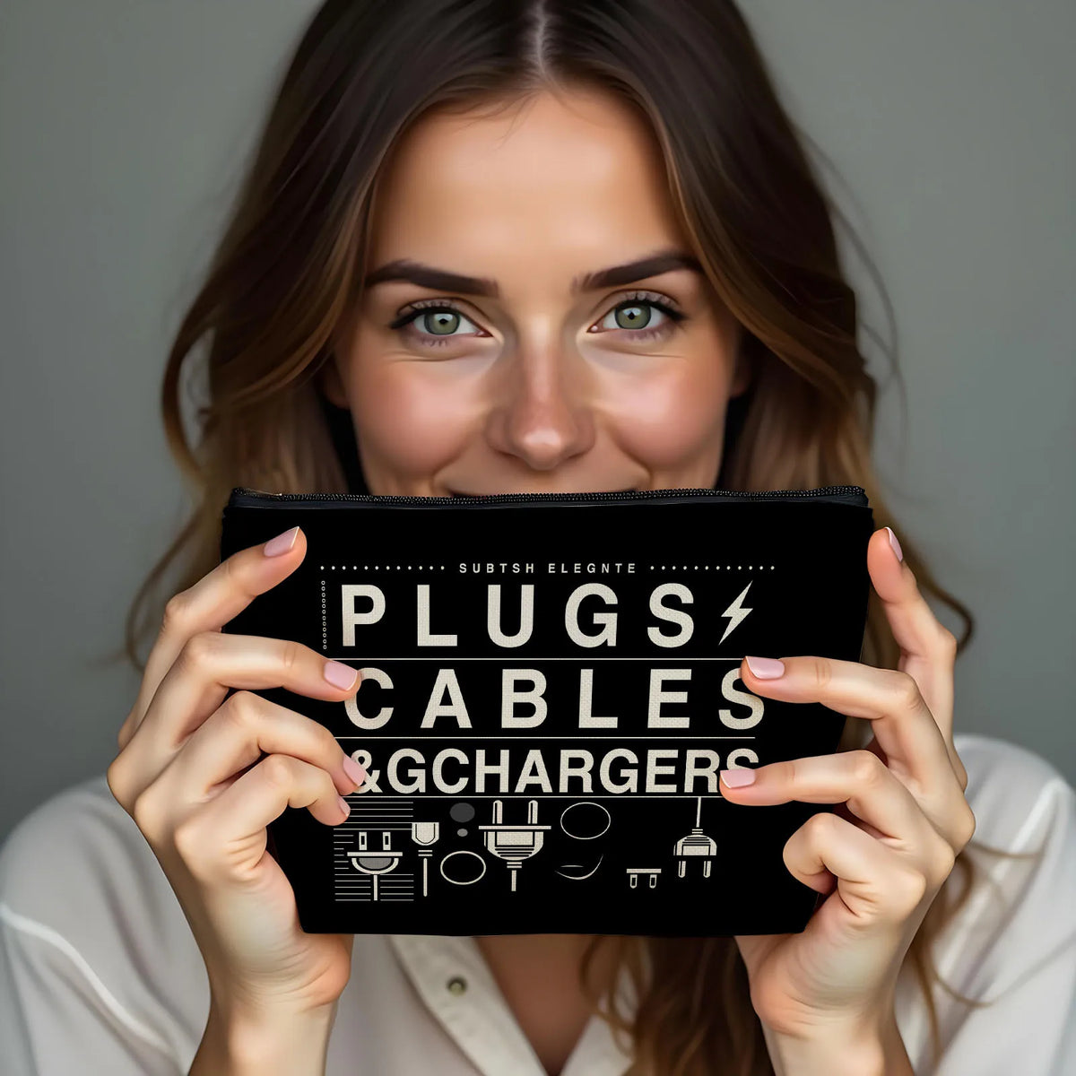 A woman holds a black zippered pouch labeled PLUGS CABLES & CHARGERS with various electronic accessories.