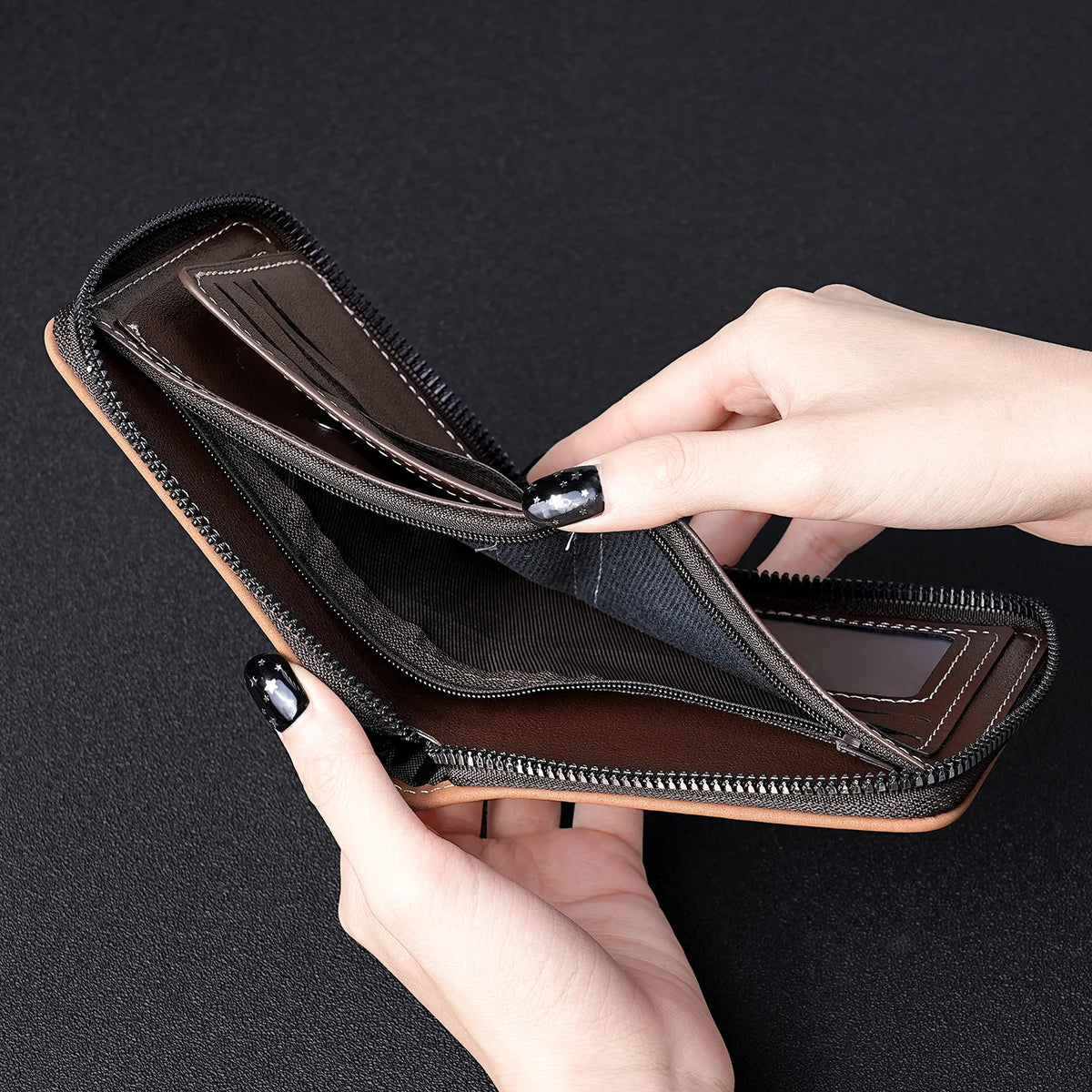 A hand opens a brown leather card clip wallet showing the interior and stitching.