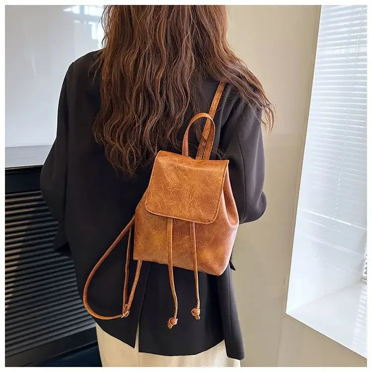Une femme tient un mini sac à dos de sport marron rétro à cordon contre un fond clair.