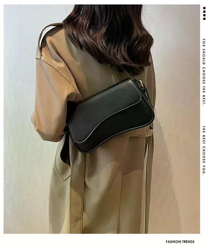 Una mujer modela un abrigo beige de gabardina y un bolso cruz de cuero negro.