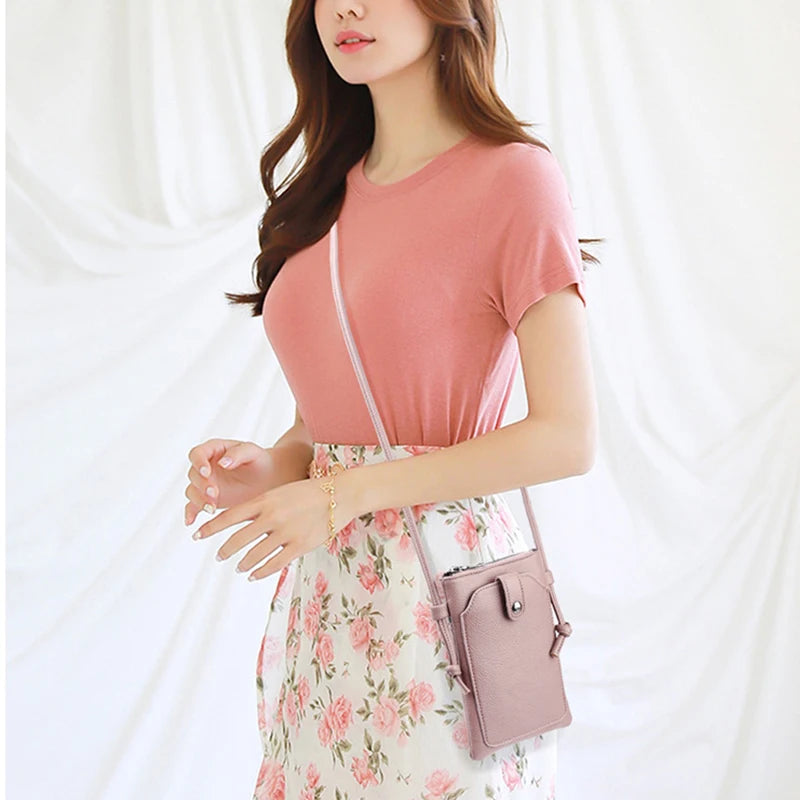 A woman wearing a pink t-shirt and floral dress carrying a mauve PU leather crossbody bag.