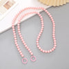 Pink acrylic bead cross phone charm necklace laid on a gray surface