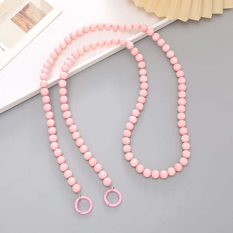 Pink acrylic bead cross phone charm necklace laid on a gray surface